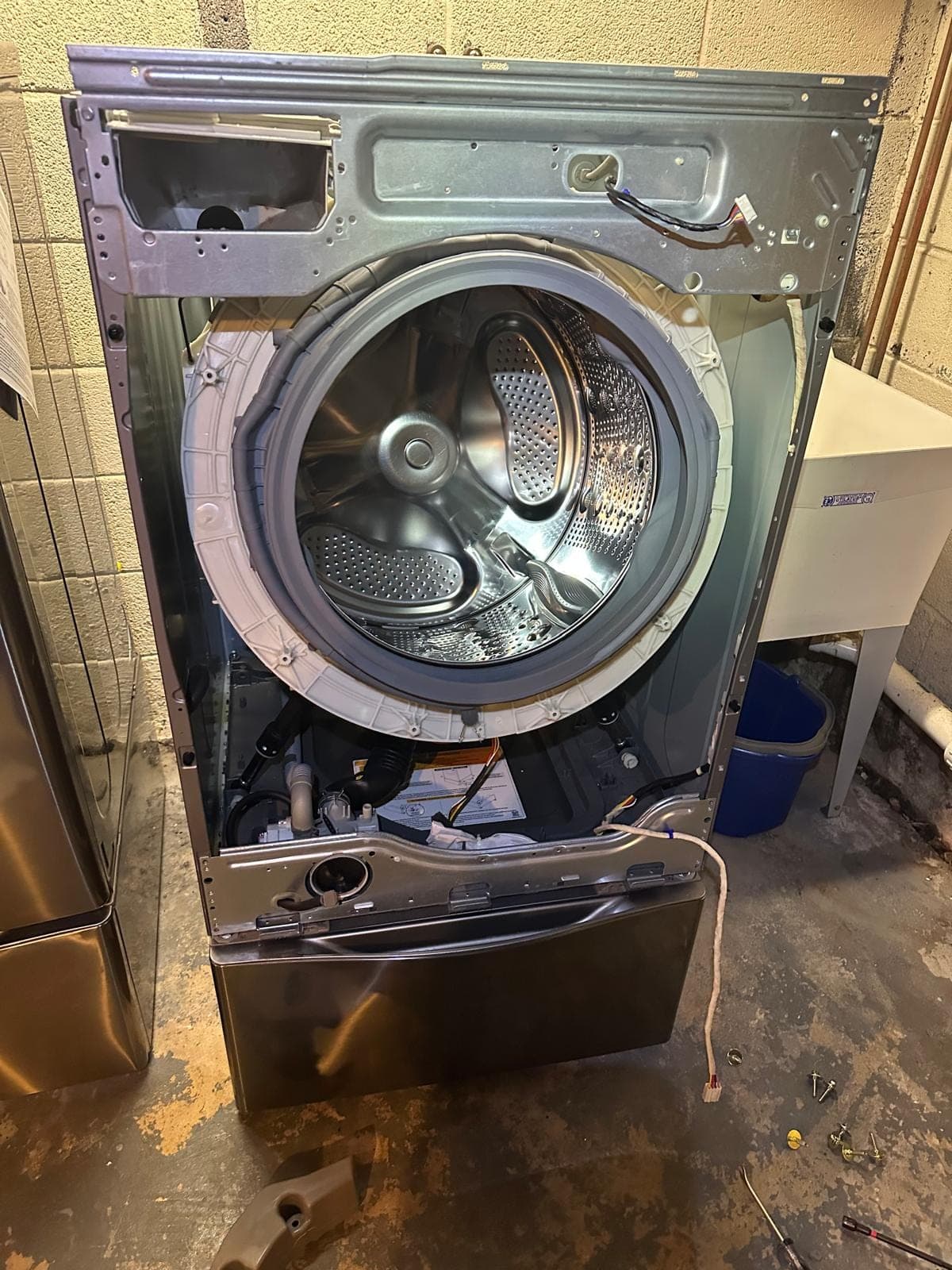 LG washer repair in Fairfax, VA — The front panel fully removed, exposing the drum, door boot seal, drain pump, and motor assembly