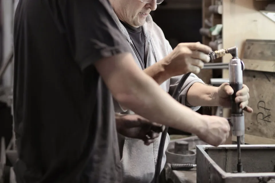 A young trainee learning handwork from a senior craftsman in a workshop