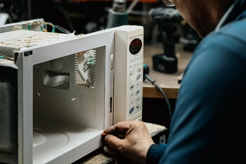 Technician repairing a microwave on a workshop bench