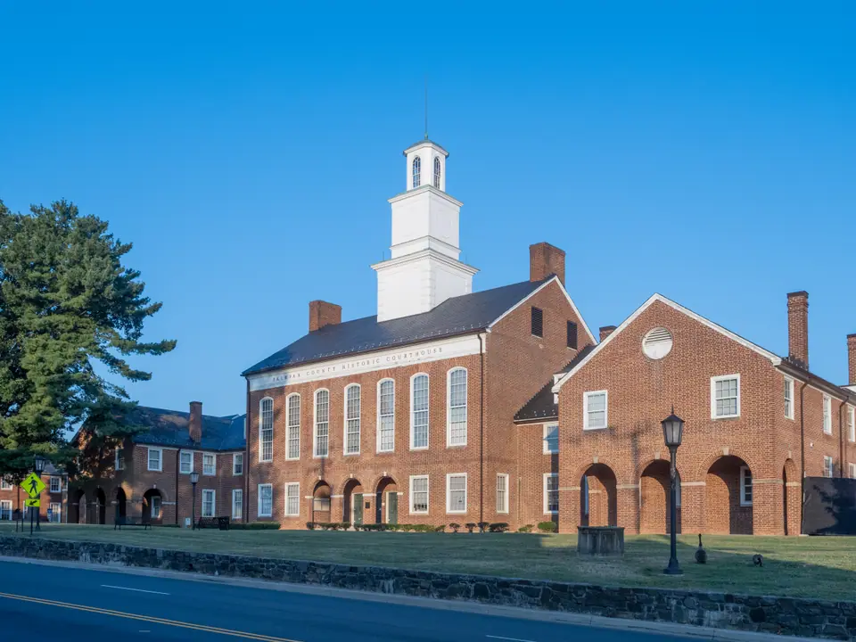 The Fairfax County Historic Courthouse on Chain Bridge Road in Old Town Fairfax, Virginia, red brick with a white cupola under a clear blue sky