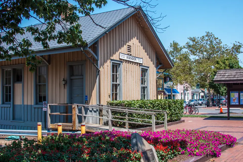 The historic Herndon Depot beside the W&OD Trail in downtown Herndon, Virginia, with flower beds in bloom