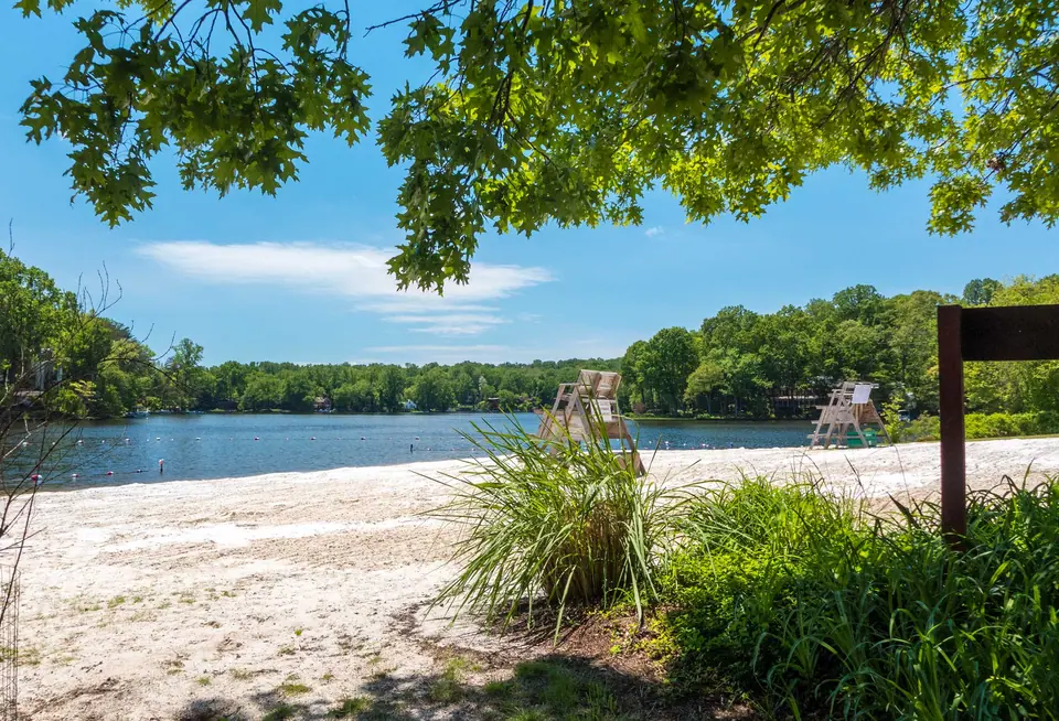 Lake Barcroft, Virginia, seen from the sand of Beach 4, with lifeguard chairs and the wooded shoreline across the water