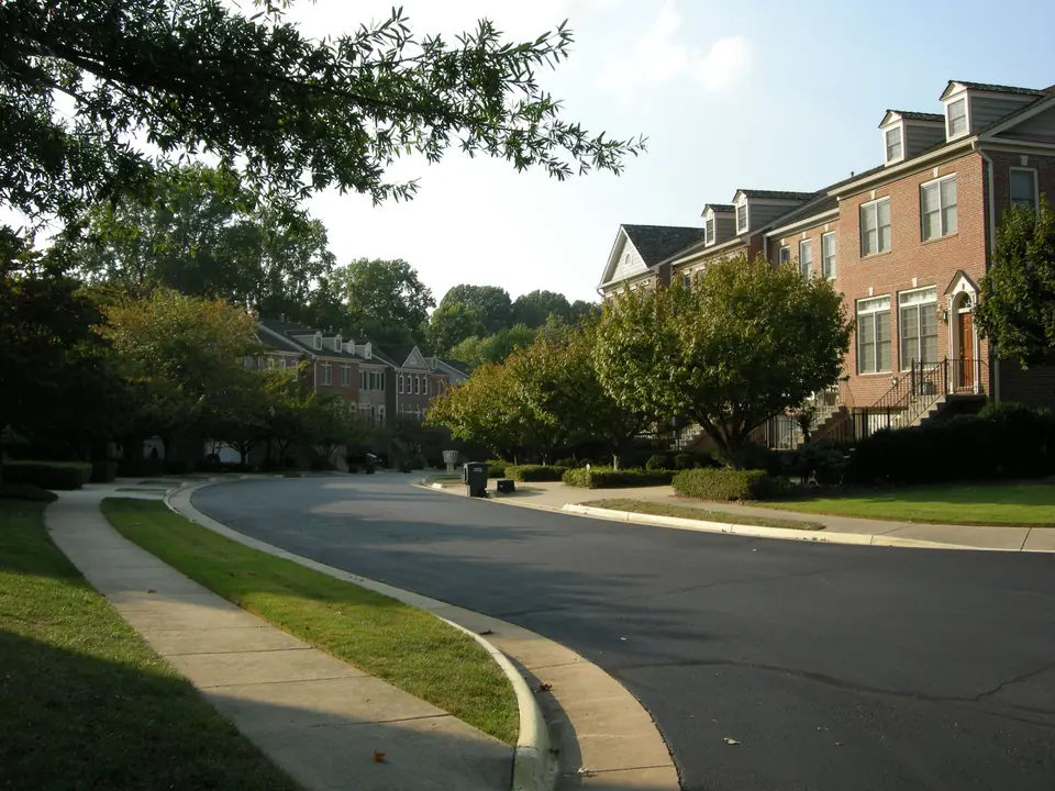 A quiet curving street of brick townhouses under mature trees in Oakton, Virginia